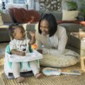 BABY EINSTEIN Podsedák na stoličku s 2 hračkami 2v1 Dine&Discover 6m+ do 23 kg