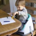 BABY EINSTEIN Podsedák na stoličku s 2 hračkami 2v1 Dine&Discover 6m+ do 23 kg