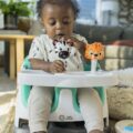 BABY EINSTEIN Podsedák na stoličku s 2 hračkami 2v1 Dine&Discover 6m+ do 23 kg